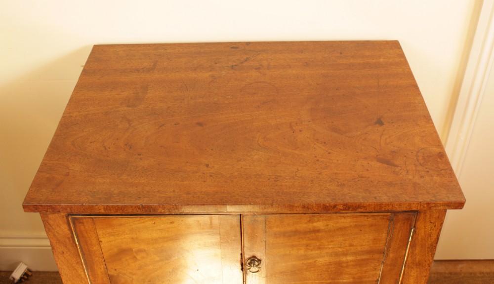 A Georgian mahogany cupboard featuring two panelled doors above a single drawer with brass swan-neck handles, supported on four straight square legs. View V