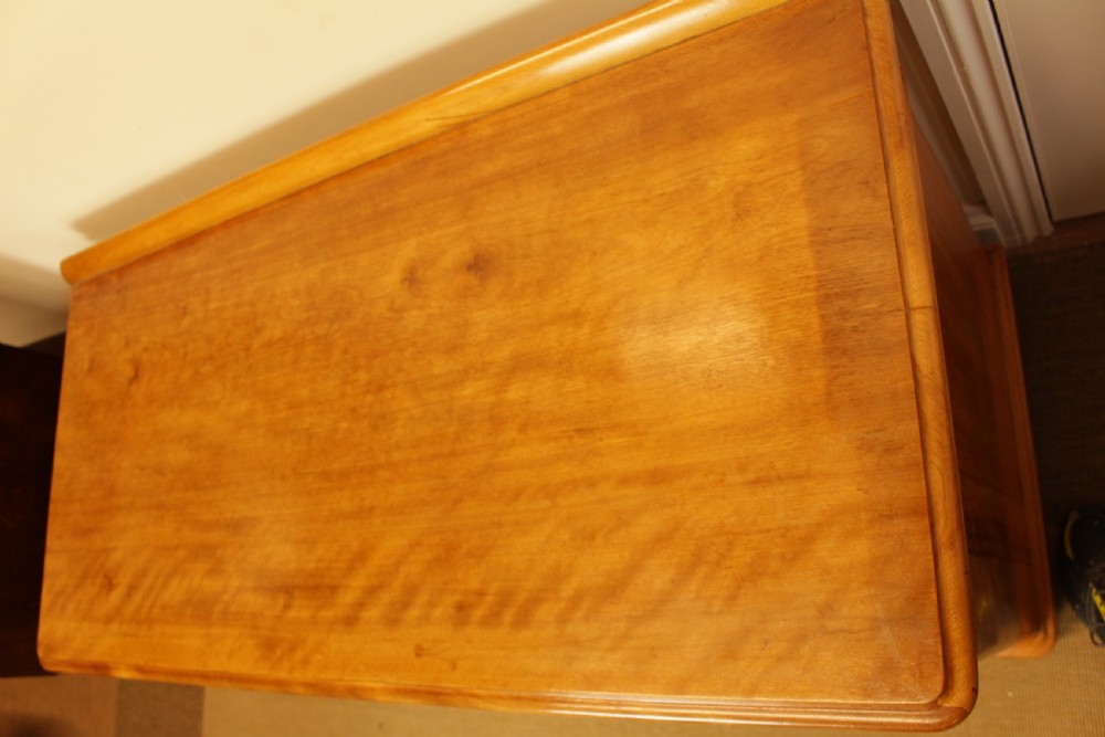 A late Victorian satin birch pedestal desk featuring nine drawers with turned handles, a low gallery back rail, and prominent golden wavy wood grain. View III