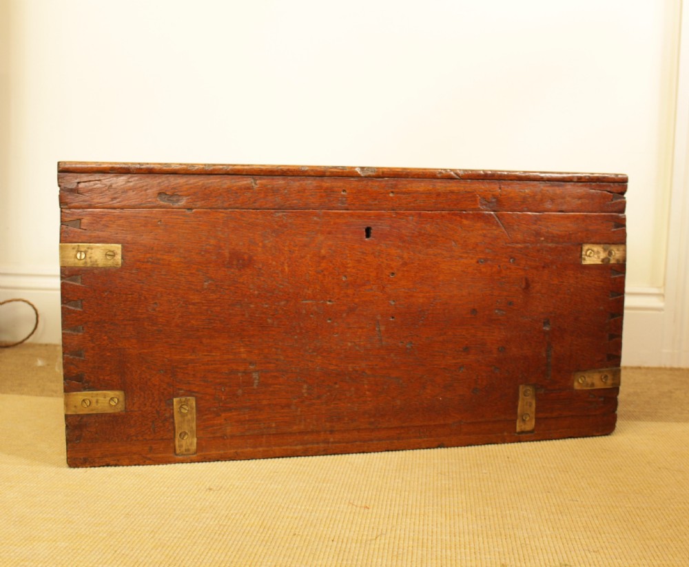 A rectangular warm brown camphorwood storage trunk featuring brass corner straps, hand-cut dovetail joints, and a central keyhole.