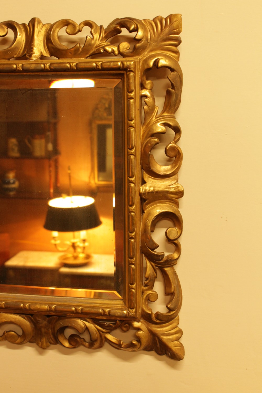 A rectangular 19th-century Italian Florentine wall mirror featuring a heavily carved pierced giltwood frame decorated with acanthus leaf motifs surrounding a bevelled glass plate. View II
