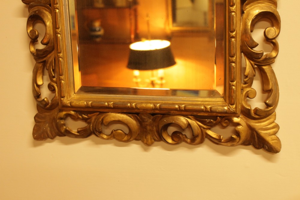 A rectangular 19th-century Italian Florentine wall mirror featuring a heavily carved pierced giltwood frame decorated with acanthus leaf motifs surrounding a bevelled glass plate. View III