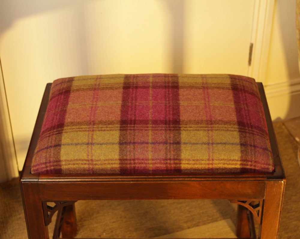 An antique mahogany dressing stool featuring straight legs, pierced stretchers, and a padded seat upholstered in a tartan wool fabric. View III