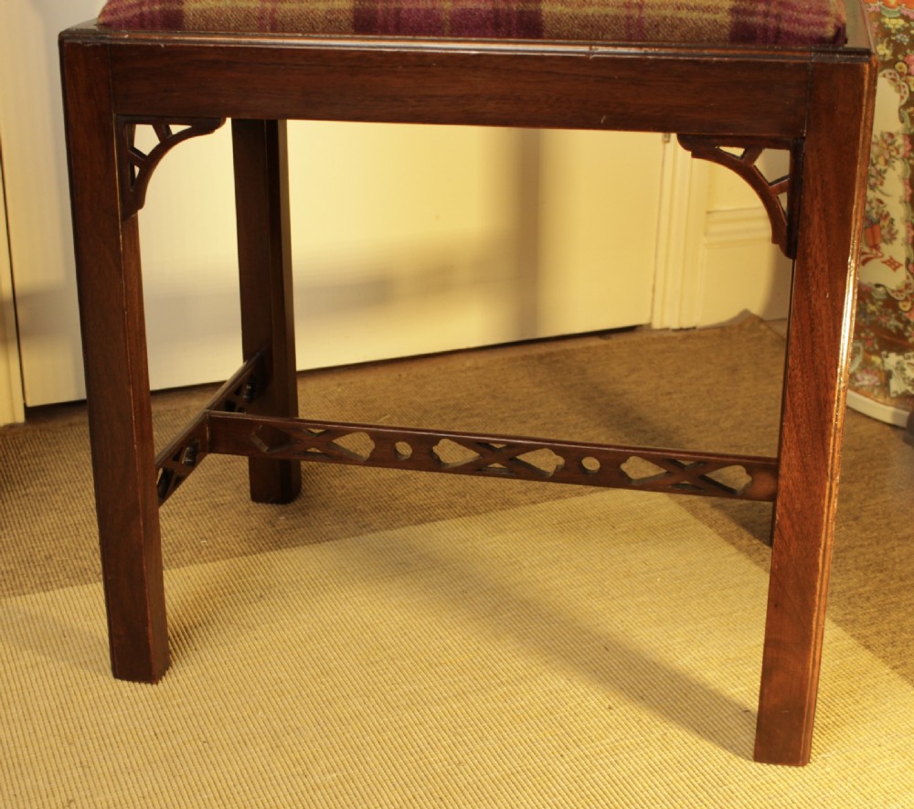 An antique mahogany dressing stool featuring straight legs, pierced stretchers, and a padded seat upholstered in a tartan wool fabric. View V