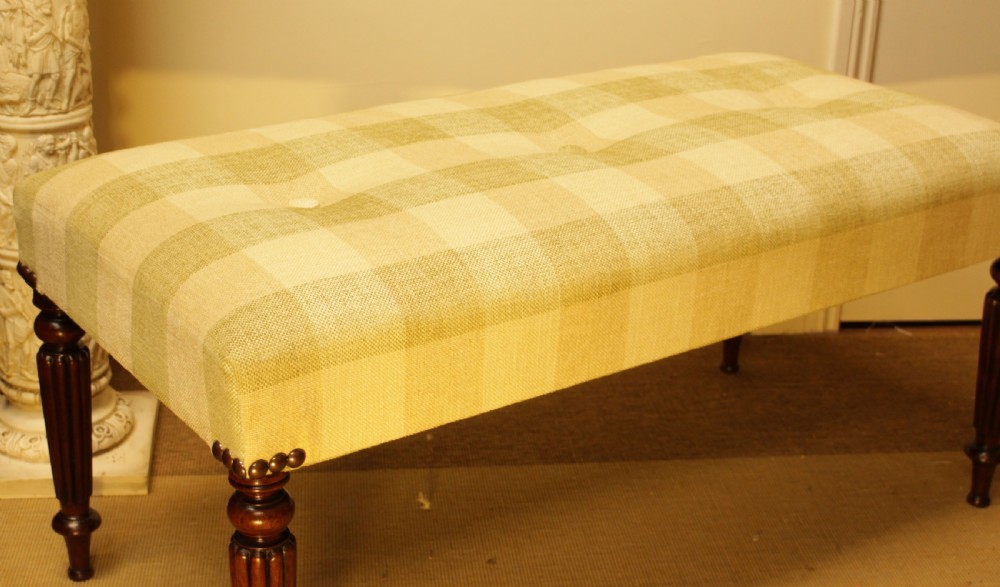 A late 19th-century mahogany stool featuring reeded turned legs, brass stud trim, and a checked cream upholstery top. View IV