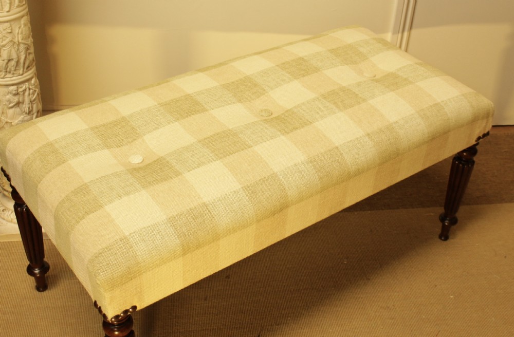 A late 19th-century mahogany stool featuring reeded turned legs, brass stud trim, and a checked cream upholstery top. View VI