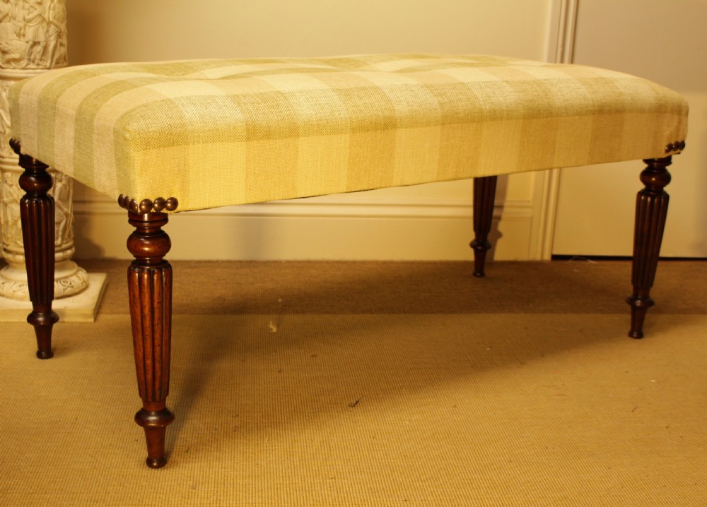 A late 19th-century mahogany stool featuring reeded turned legs, brass stud trim, and a checked cream upholstery top. View VII