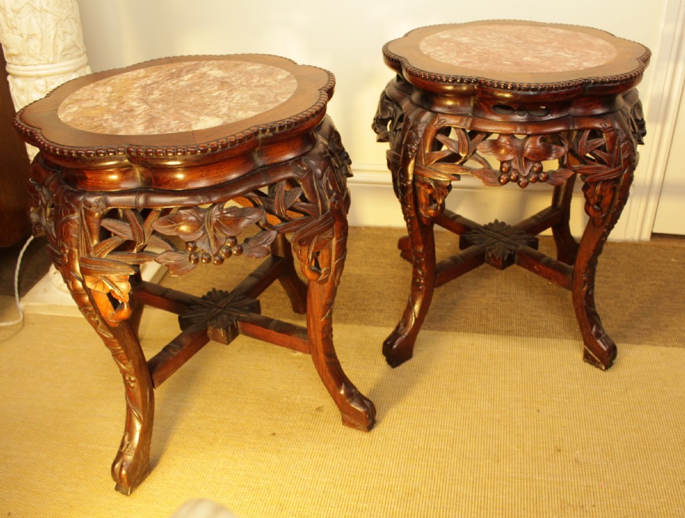 A pair of carved dark rosewood Chinese urn stands featuring lobed frames with inset circular rouge marble tops and intricate foliage aprons. View III