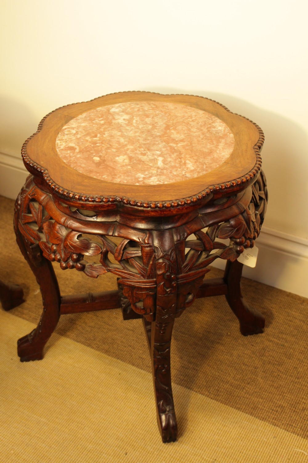 A pair of carved dark rosewood Chinese urn stands featuring lobed frames with inset circular rouge marble tops and intricate foliage aprons. View IV