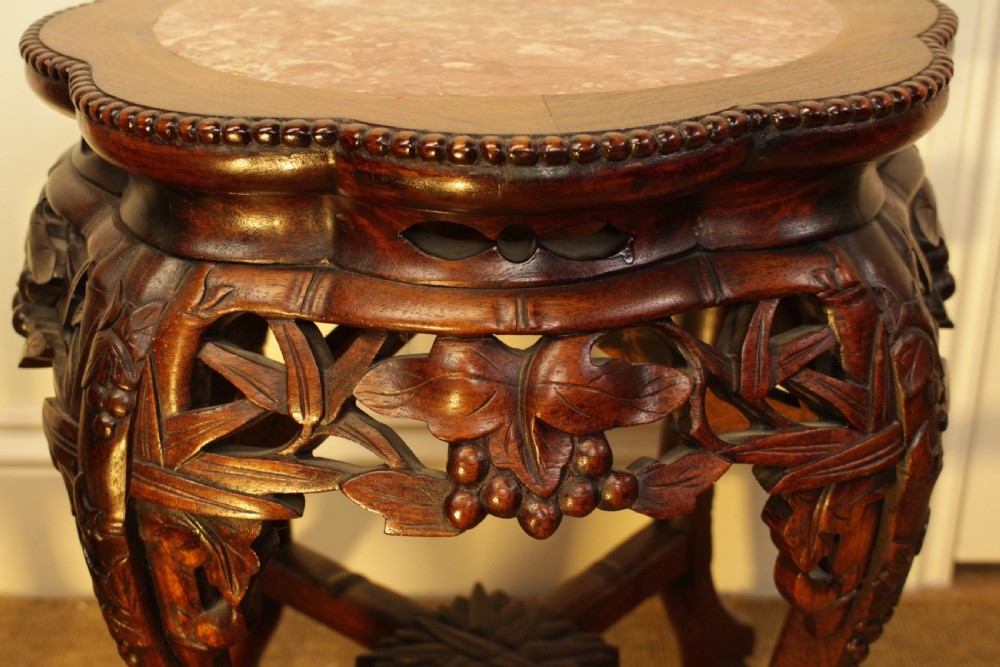 A pair of carved dark rosewood Chinese urn stands featuring lobed frames with inset circular rouge marble tops and intricate foliage aprons. View V