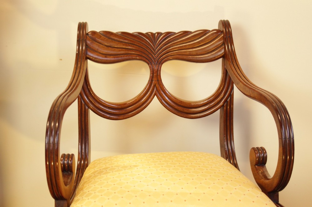 A Regency mahogany armchair featuring a carved fan-motif backrest, reeded sweeping arms with scroll ends, and a pale yellow upholstered seat. View II