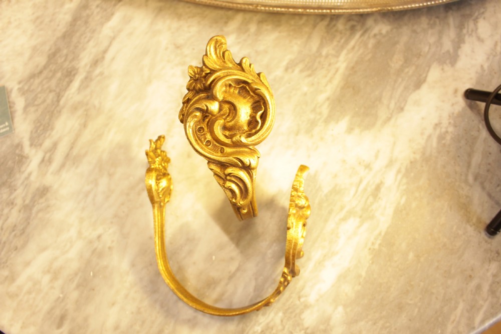 A pair of French Rococo gilt bronze curtain tiebacks featuring sculpted acanthus leaves and scrolling motifs.
