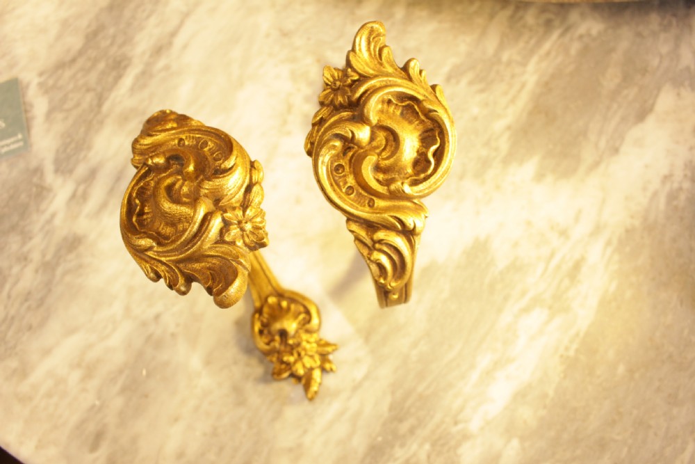 A pair of French Rococo gilt bronze curtain tiebacks featuring sculpted acanthus leaves and scrolling motifs. View V