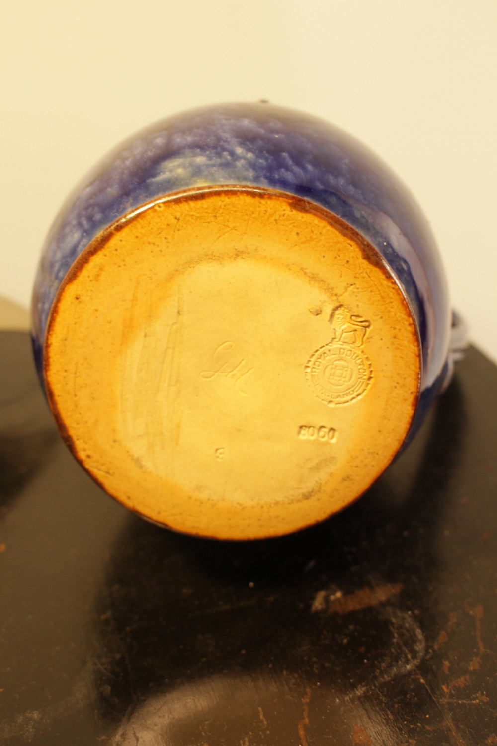 A Royal Doulton salt-glazed stoneware water jug featuring a cobalt blue body with raised relief scrollwork, an ochre neck, and a hinged metal lid. View IV