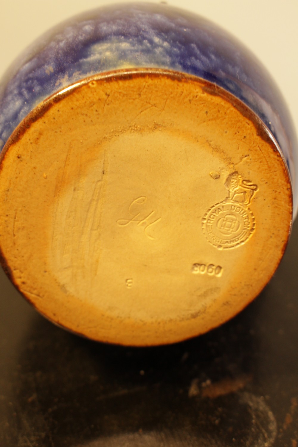A Royal Doulton salt-glazed stoneware water jug featuring a cobalt blue body with raised relief scrollwork, an ochre neck, and a hinged metal lid. View V