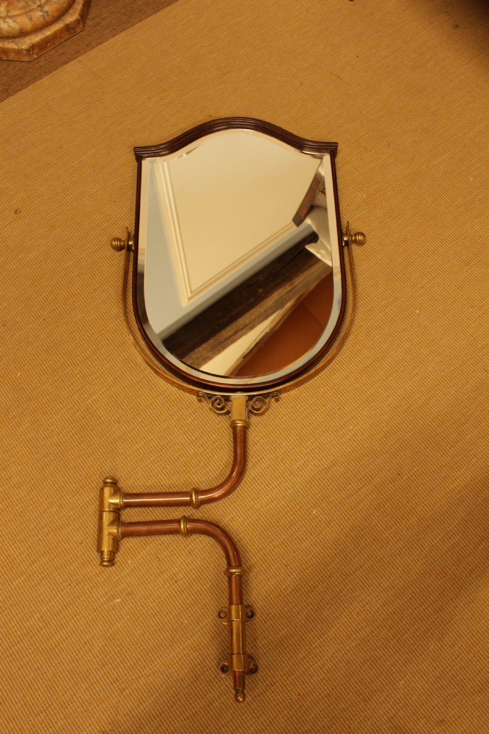 A shield-shaped mahogany framed mirror mounted on an adjustable tubular copper arm with polished brass fixtures. View II