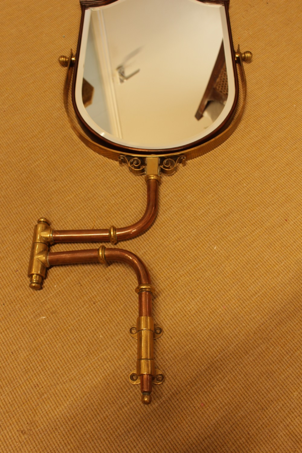 A shield-shaped mahogany framed mirror mounted on an adjustable tubular copper arm with polished brass fixtures. View III