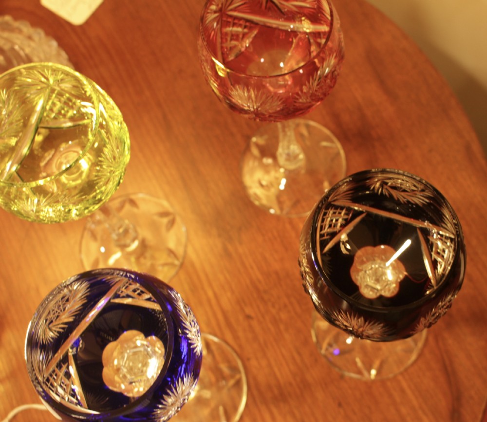 A set of four Bohemian cut-to-clear crystal hock wine glasses in red, blue, green, and dark violet with tall faceted clear stems. View VI