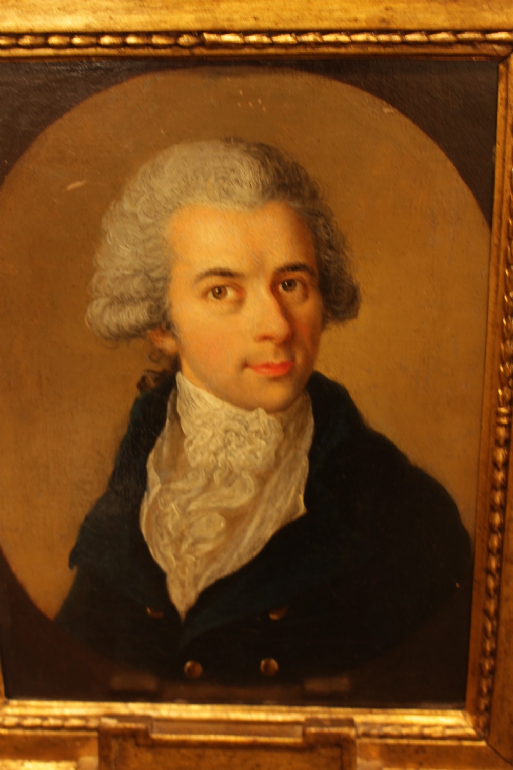 An eighteenth-century oil painting on canvas depicting a gentleman with a lace cravat set within a painted oval, framed in a carved gilded timber border. View V