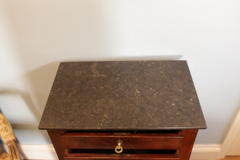 A French Empire flame mahogany side table featuring a dark grey marble top, three drawers with brass keyholes, turned column front legs, and an undertier shelf. View III