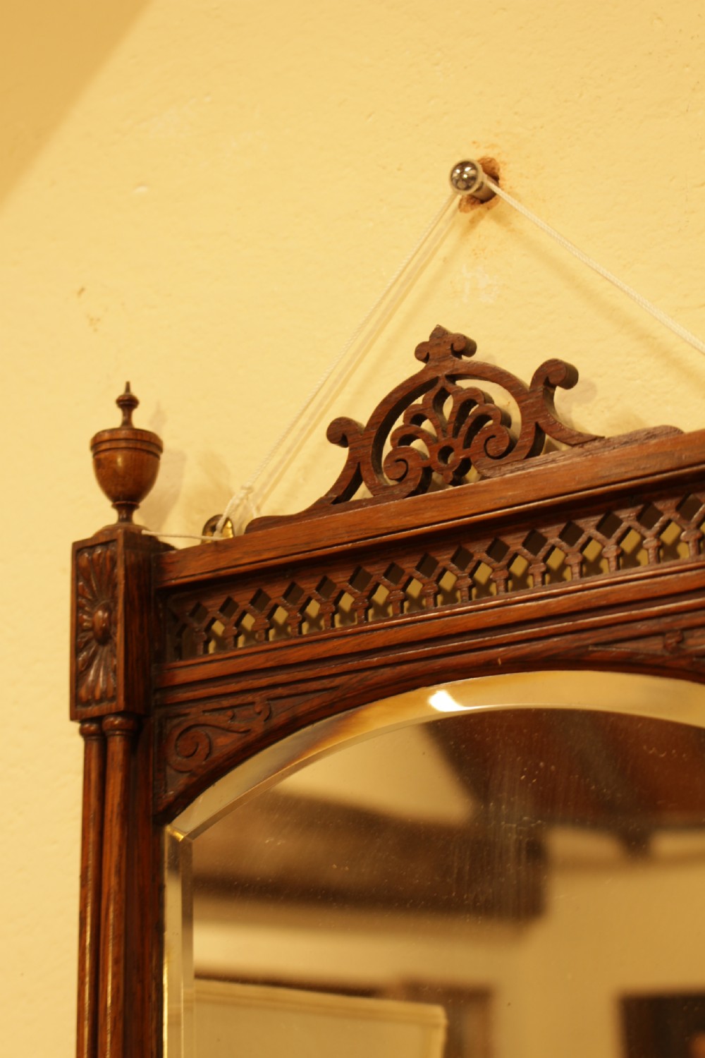 A 19th-century carved rosewood wall mirror featuring an integrated shelf with fretwork gallery, turned side columns, finials, and a bevelled mirror glass plate. View V