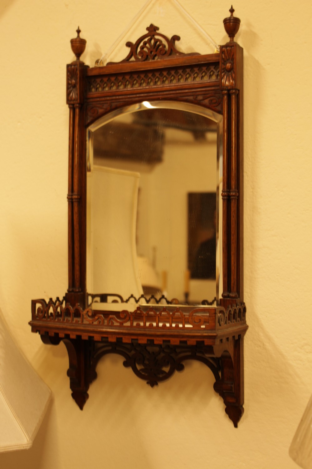 A 19th-century carved rosewood wall mirror featuring an integrated shelf with fretwork gallery, turned side columns, finials, and a bevelled mirror glass plate. View VII