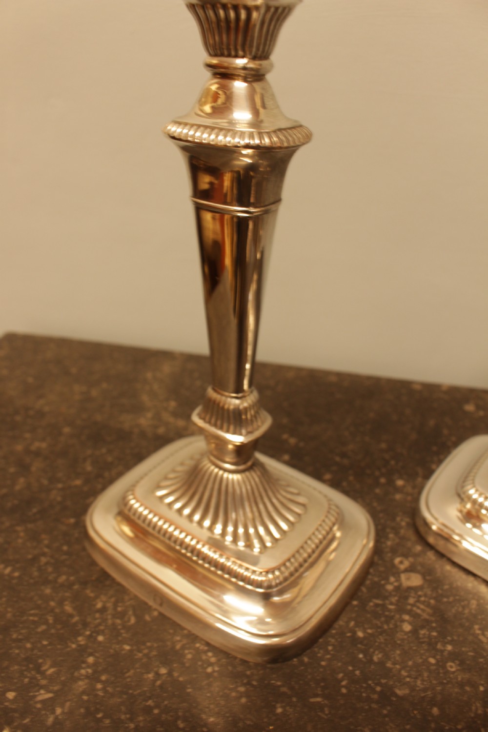 A pair of silver-plated candlesticks featuring turned fluted stems and gadrooned square bases. View II