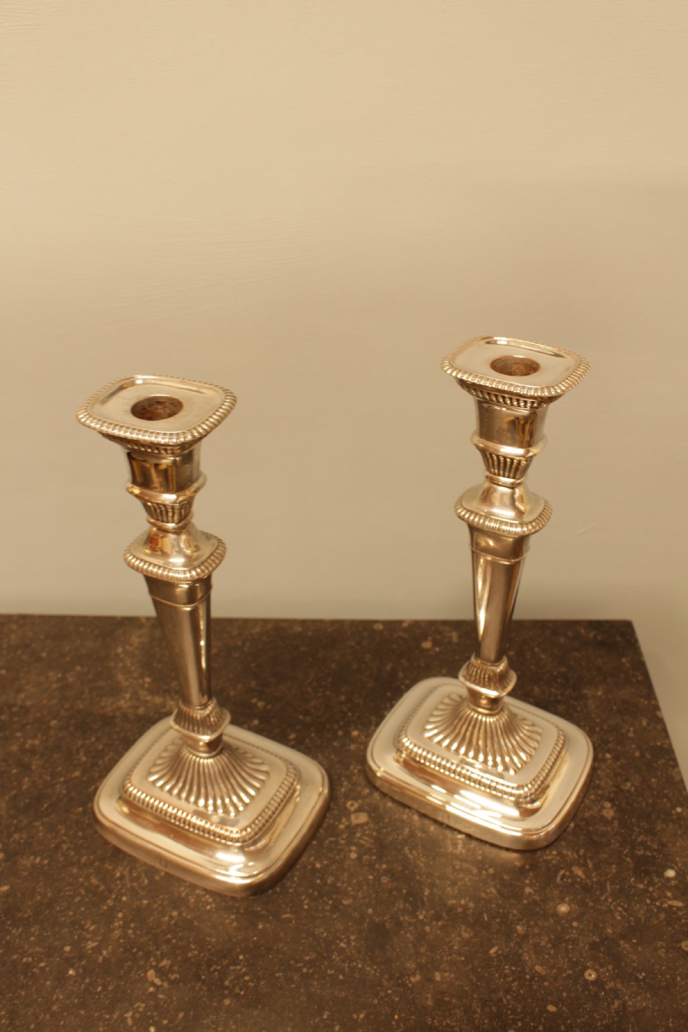 A pair of silver-plated candlesticks featuring turned fluted stems and gadrooned square bases. View III