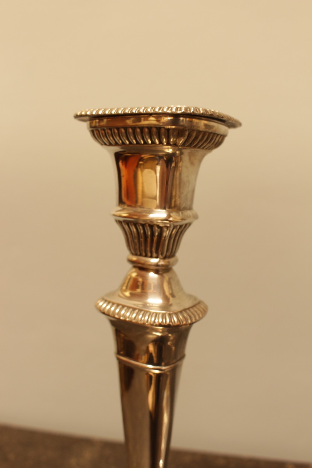 A pair of silver-plated candlesticks featuring turned fluted stems and gadrooned square bases. View IV