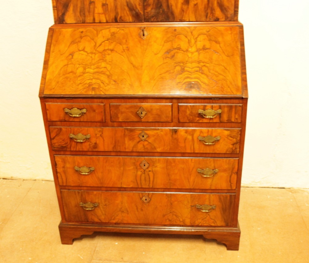 An eighteenth-century walnut bureau bookcase featuring two cupboard doors over a slant-front writing flap with four lower drawers and brass handles. View II