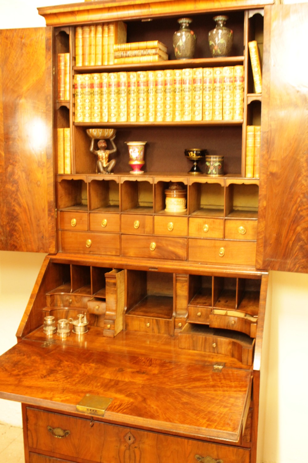 An eighteenth-century walnut bureau bookcase featuring two cupboard doors over a slant-front writing flap with four lower drawers and brass handles. View IV