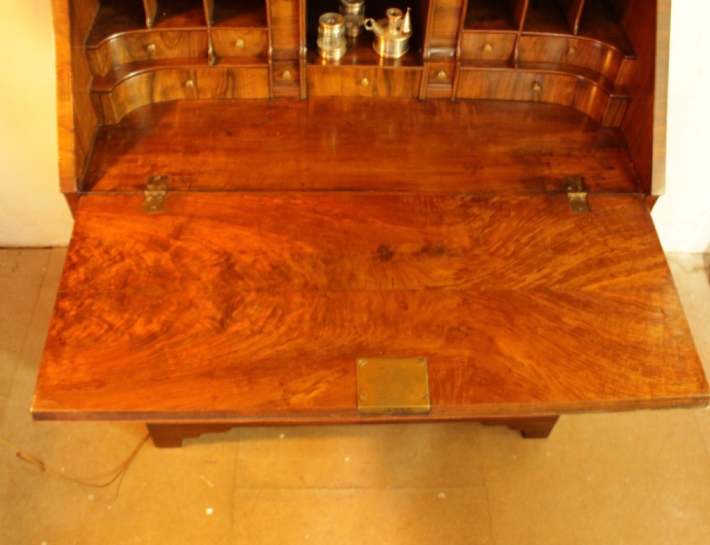An eighteenth-century walnut bureau bookcase featuring two cupboard doors over a slant-front writing flap with four lower drawers and brass handles. View VII