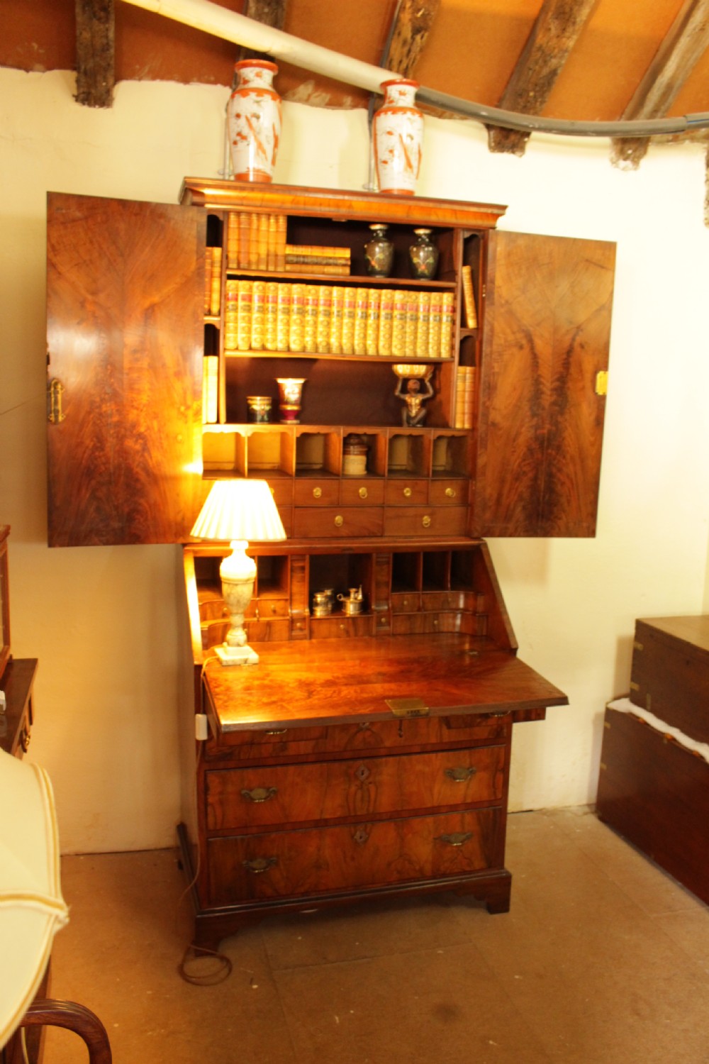 An eighteenth-century walnut bureau bookcase featuring two cupboard doors over a slant-front writing flap with four lower drawers and brass handles. View X