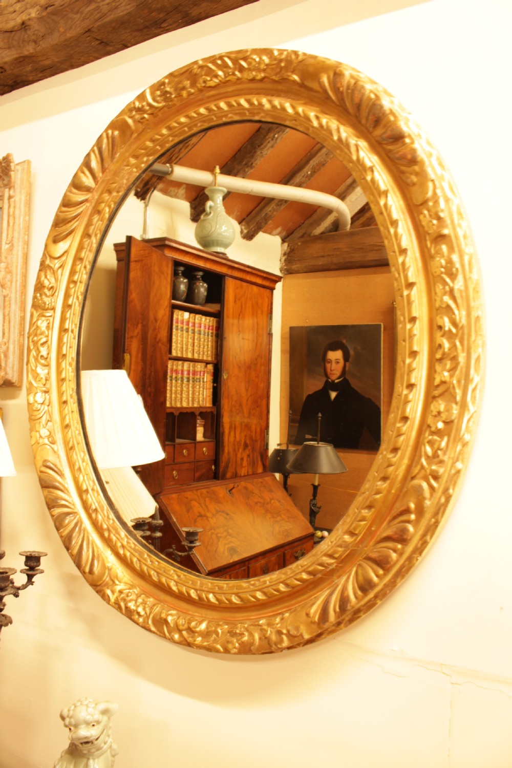 A large 18th-century Georgian oval wall mirror featuring a hand-carved giltwood frame decorated with acanthus leaf motifs. View V