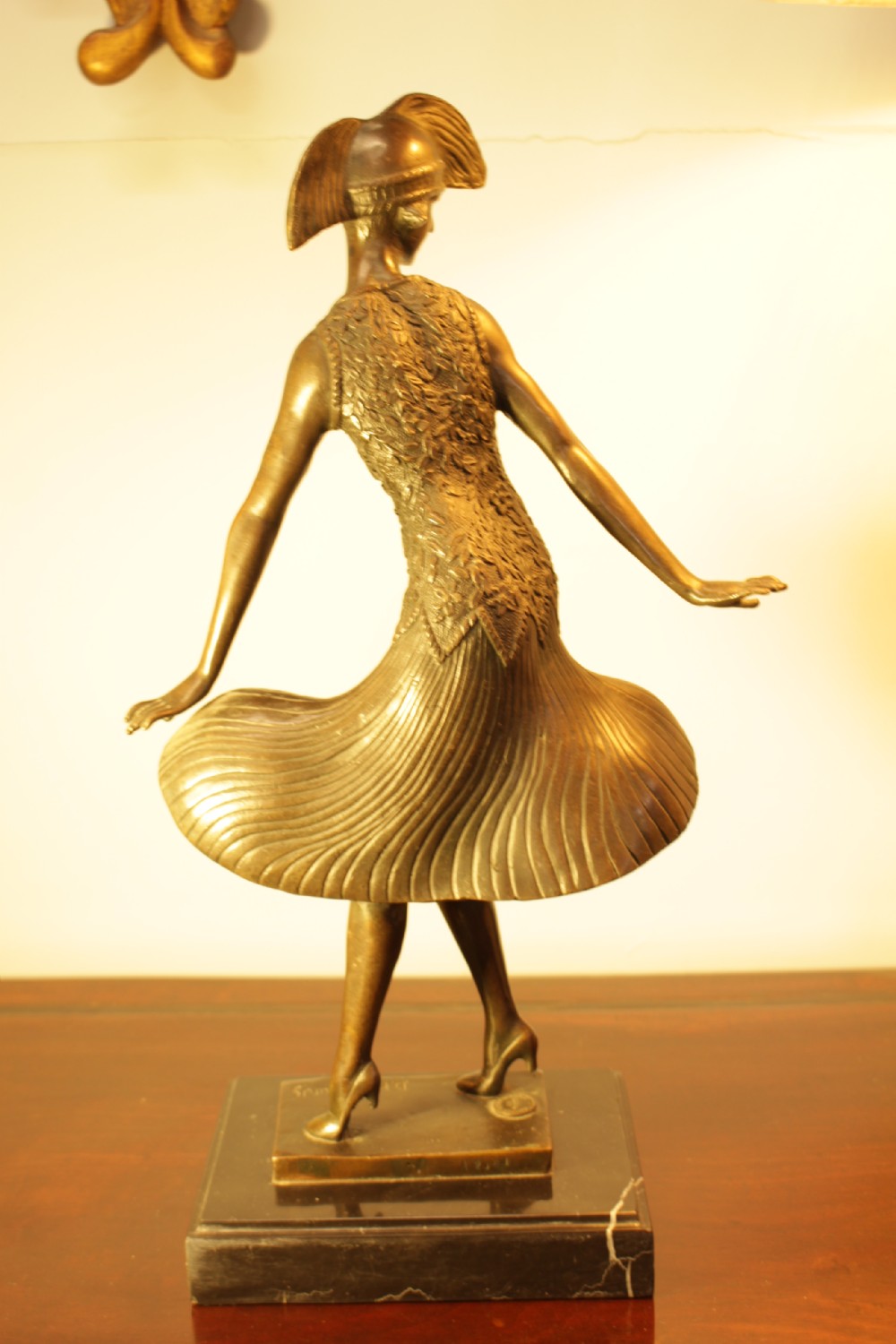 An Art Deco bronze sculpture depicting a stylized female dancer in a pleated dress and cloche headpiece mounted on a marble base. View II