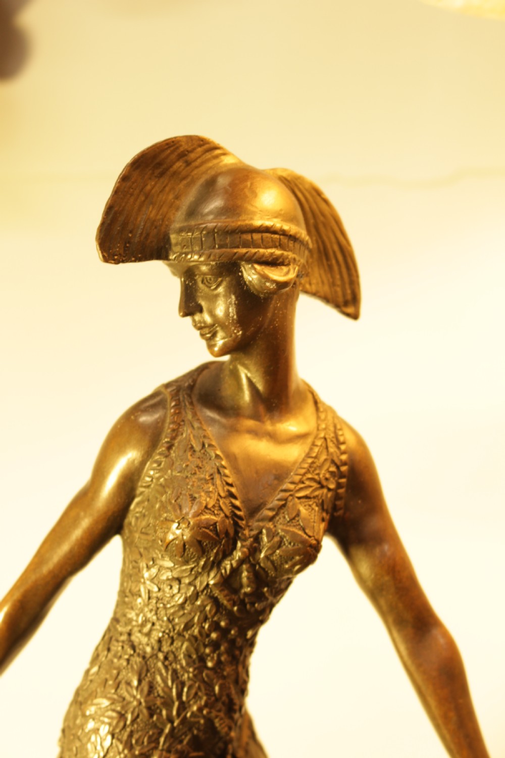 An Art Deco bronze sculpture depicting a stylized female dancer in a pleated dress and cloche headpiece mounted on a marble base. View III