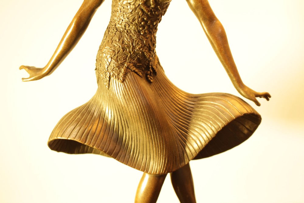 An Art Deco bronze sculpture depicting a stylized female dancer in a pleated dress and cloche headpiece mounted on a marble base. View V