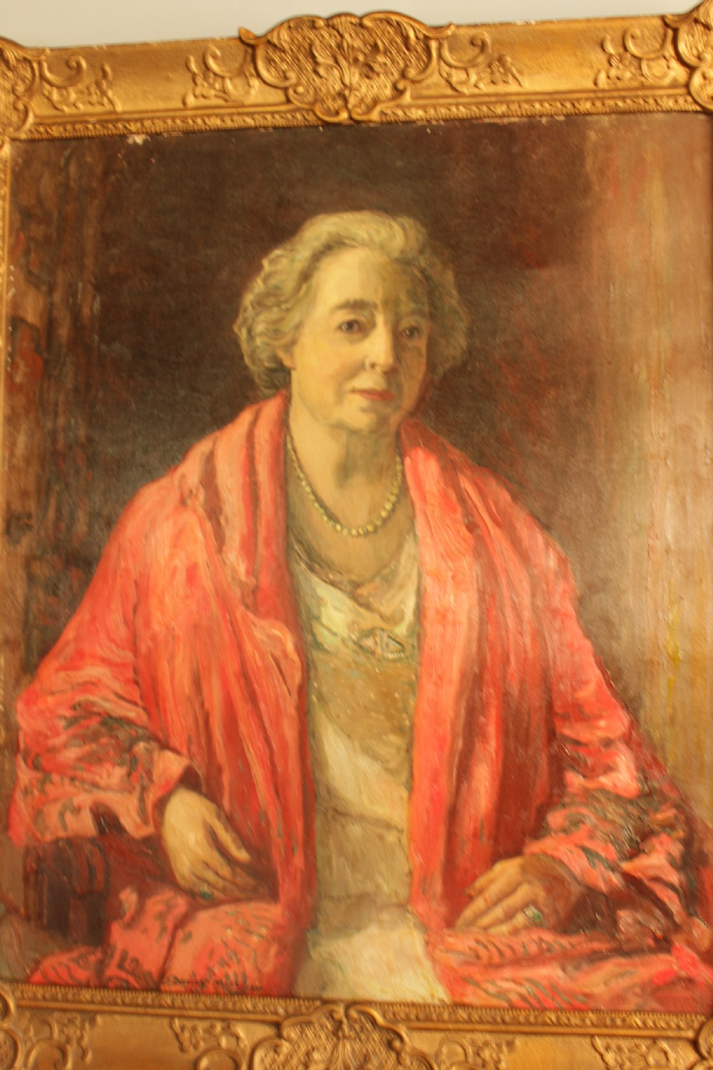 An oil painting depicting a seated woman wearing a coral shawl and a necklace, set within an ornate carved gilt frame. View III