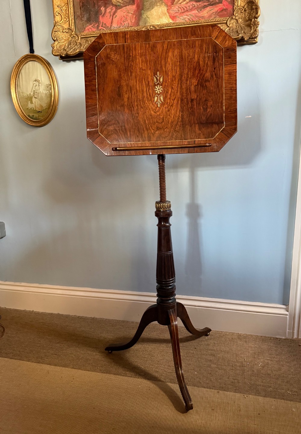 A nineteenth-century dark rosewood adjustable music stand on a turned pedestal stem and tripod base with central brass inlay on the rectangular slant top.