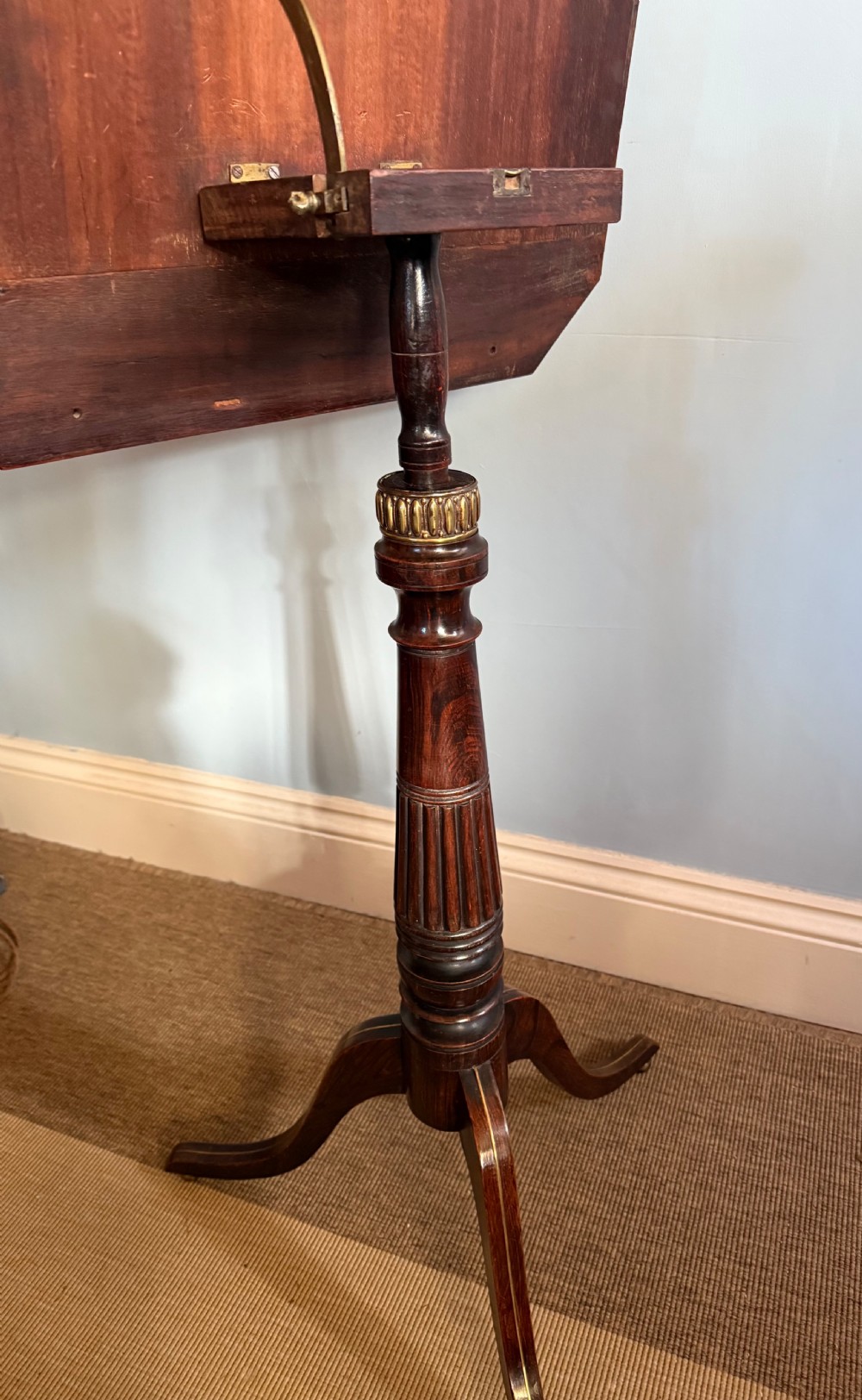 A nineteenth-century dark rosewood adjustable music stand on a turned pedestal stem and tripod base with central brass inlay on the rectangular slant top. View V