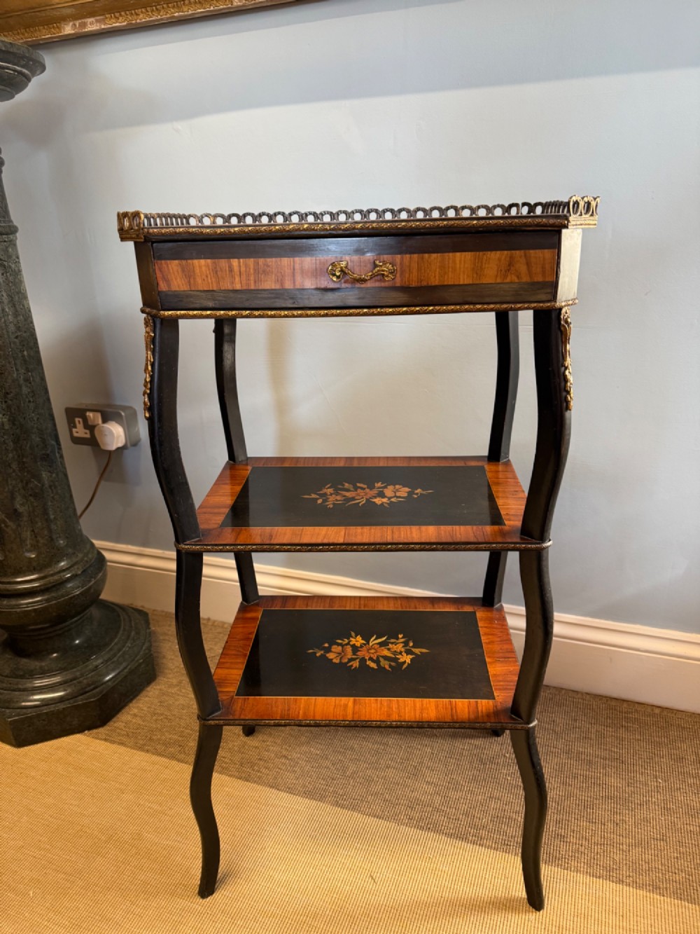 A three-tiered French ebonised walnut whatnot table with marquetry floral inlays, a single drawer, cabriole legs, and a pierced brass top gallery. View IV