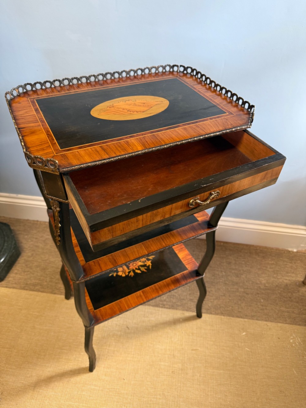 A three-tiered French ebonised walnut whatnot table with marquetry floral inlays, a single drawer, cabriole legs, and a pierced brass top gallery. View V