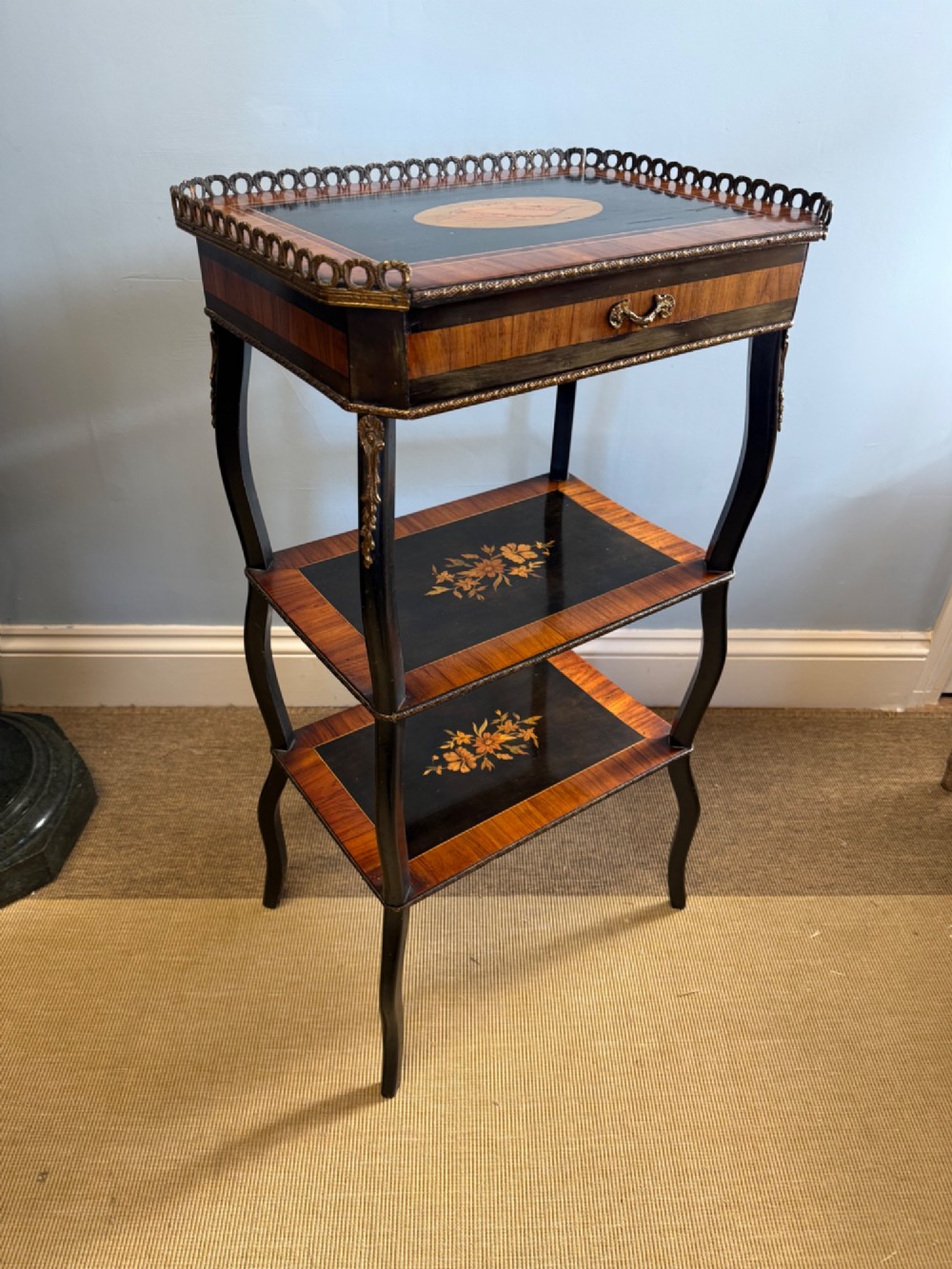 A three-tiered French ebonised walnut whatnot table with marquetry floral inlays, a single drawer, cabriole legs, and a pierced brass top gallery. View VI