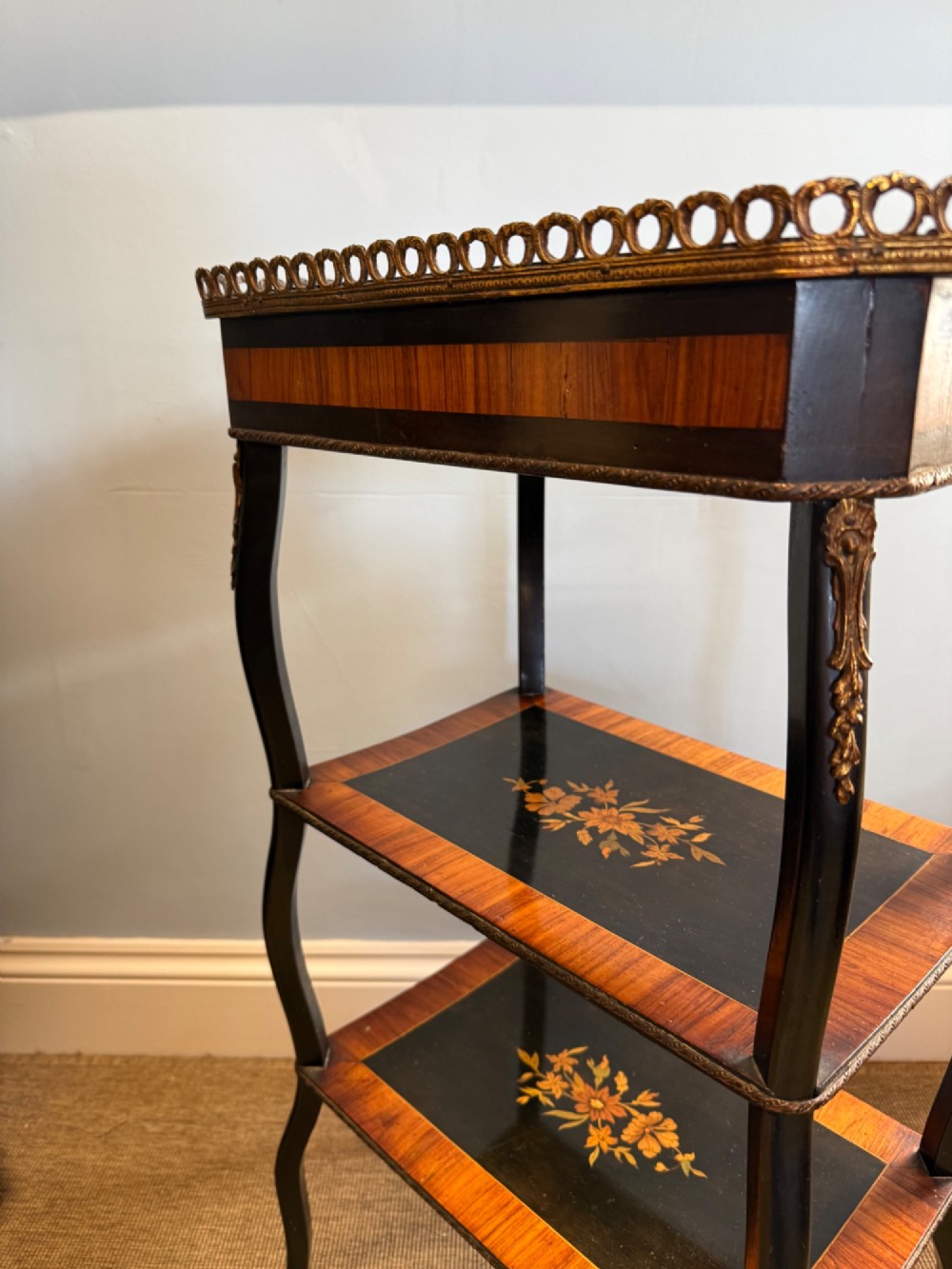 A three-tiered French ebonised walnut whatnot table with marquetry floral inlays, a single drawer, cabriole legs, and a pierced brass top gallery. View IX