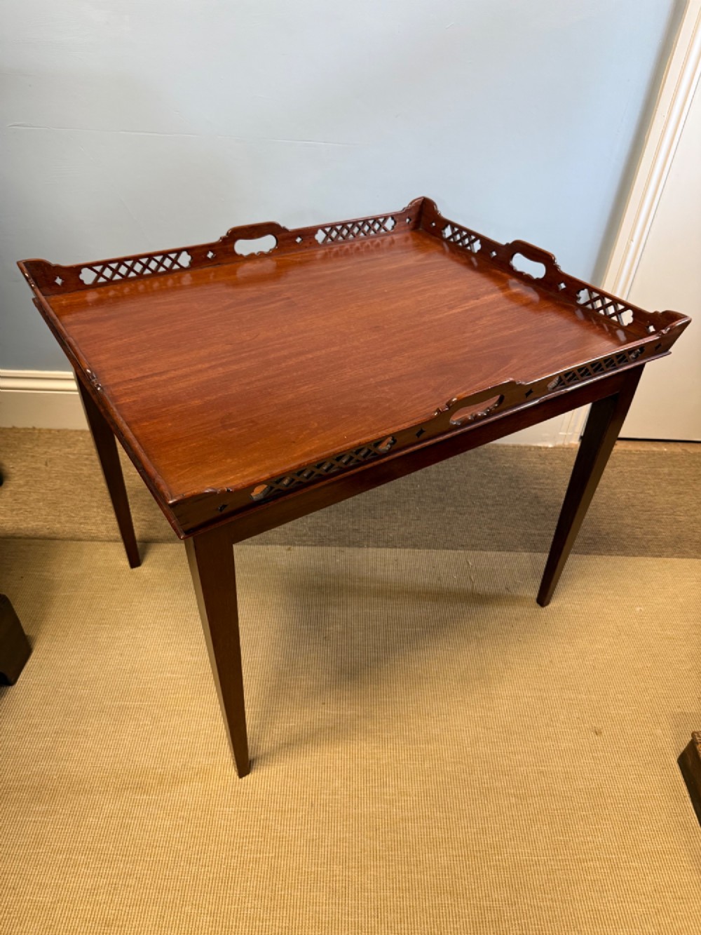 A late nineteenth-century mahogany tray top table featuring a pierced fretwork gallery, integrated cut-out side handles, and four square tapered legs.