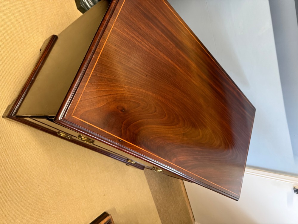 A Georgian mahogany three-drawer chest featuring decorative boxwood stringing, brass oval drop handles, keyhole escutcheons, and bracket feet. View II