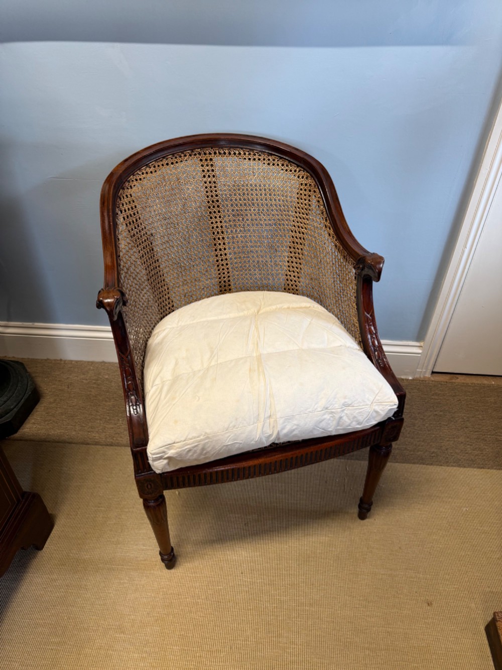 An antique mahogany bergere armchair featuring hand-woven cane panels, a curved backrest, fluted seat rail, and turned front legs. View III