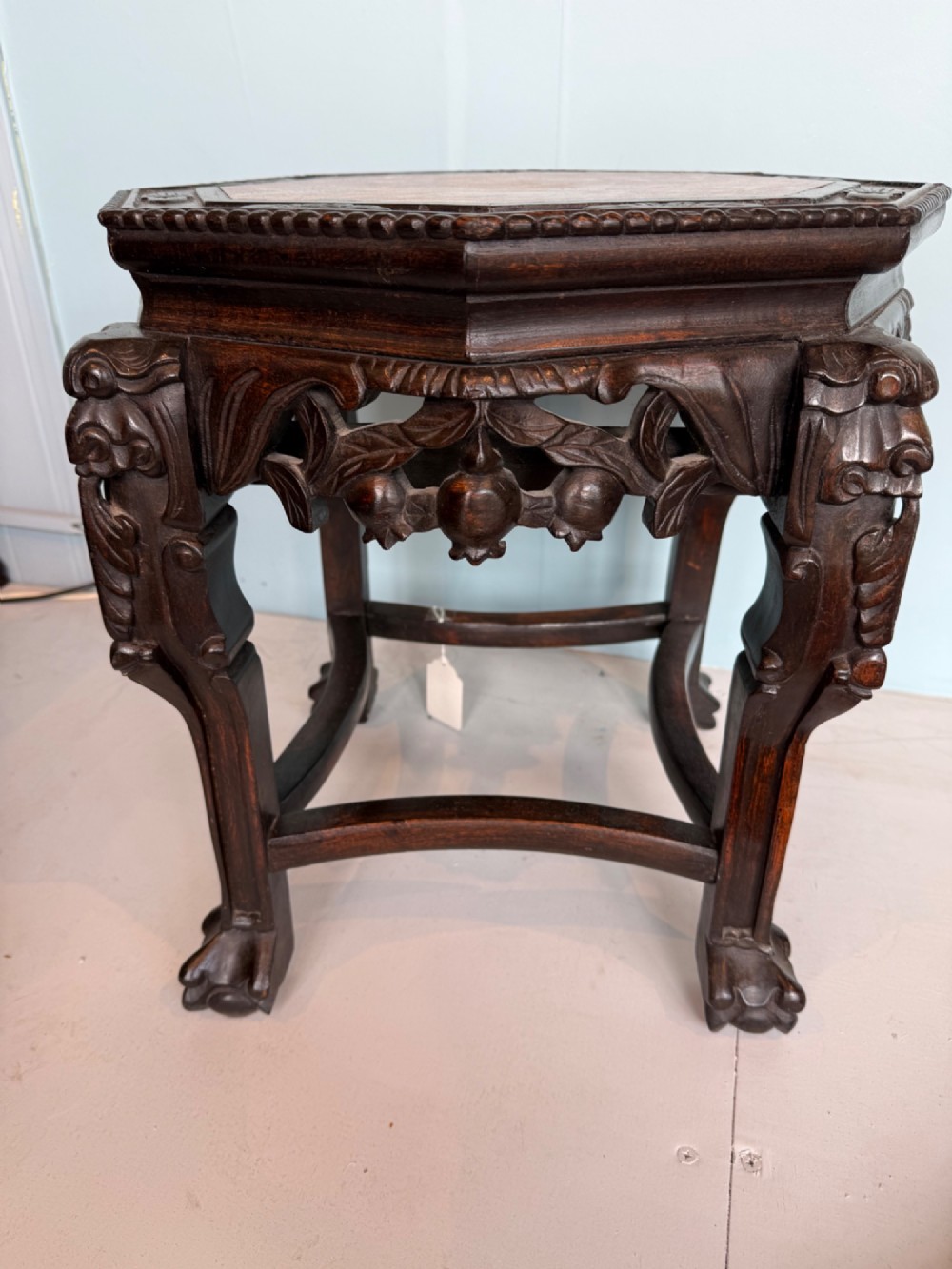 An octagonal dark carved hardwood stand featuring an inset pink marble top, openwork apron detailing, and cabriole legs. View III