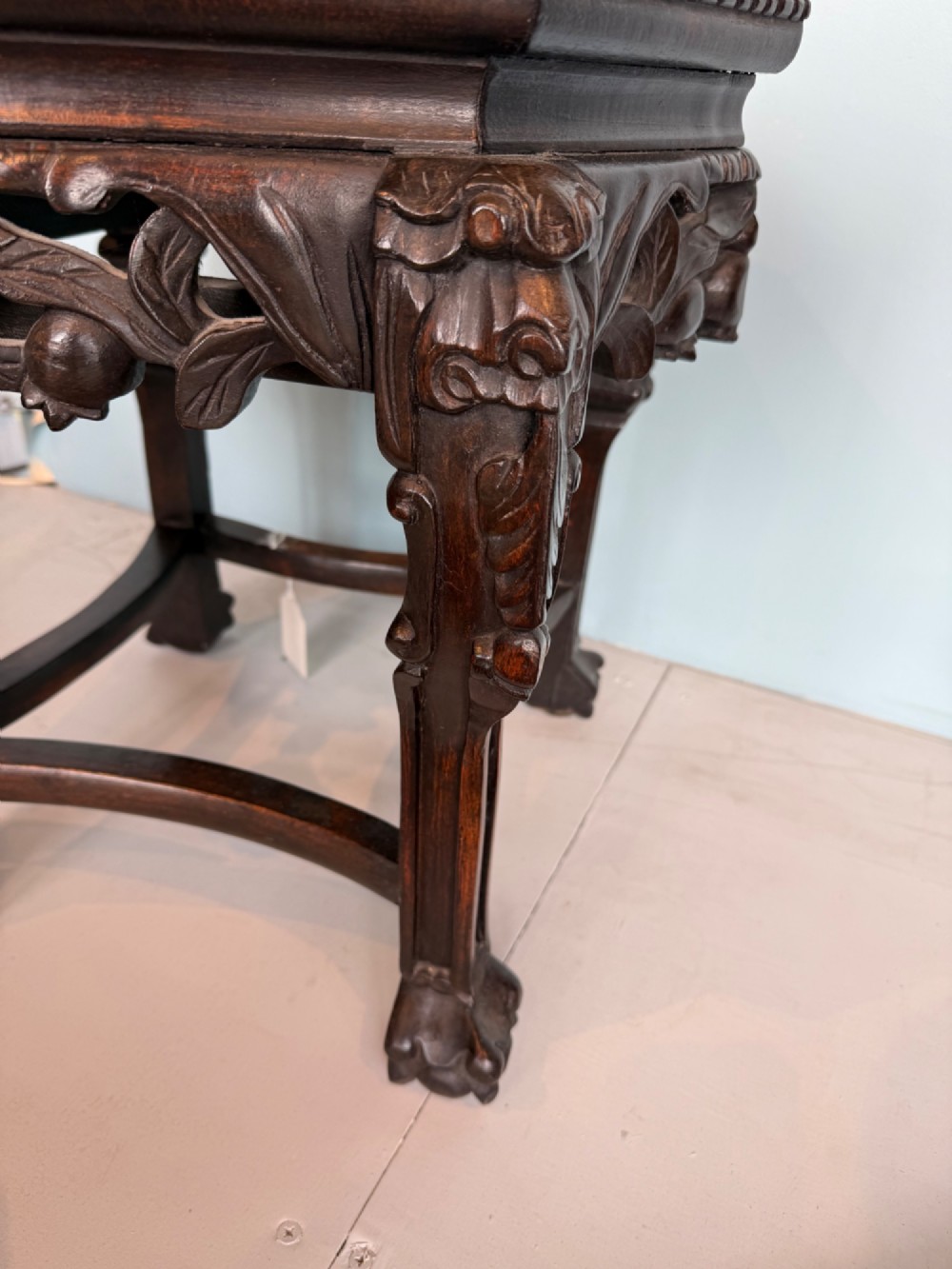 An octagonal dark carved hardwood stand featuring an inset pink marble top, openwork apron detailing, and cabriole legs. View V