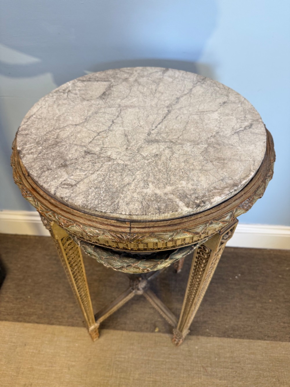 A tall 19th-century French Neoclassical style plant stand featuring a circular grey marble top, carved cream and parcel-gilded legs with swags, and a central X-stretcher. View II