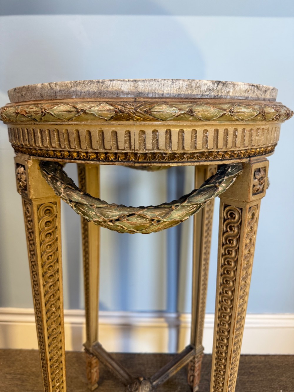 A tall 19th-century French Neoclassical style plant stand featuring a circular grey marble top, carved cream and parcel-gilded legs with swags, and a central X-stretcher. View III